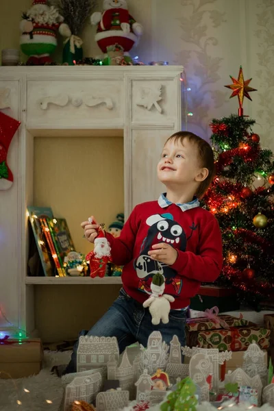 Child opening present at Christmas tree at home. Little baby boy sweet. Surprise, celebration.