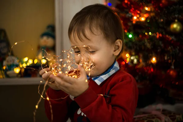 Child opening present at Christmas tree at home. Little baby boy sweet. Surprise, celebration.