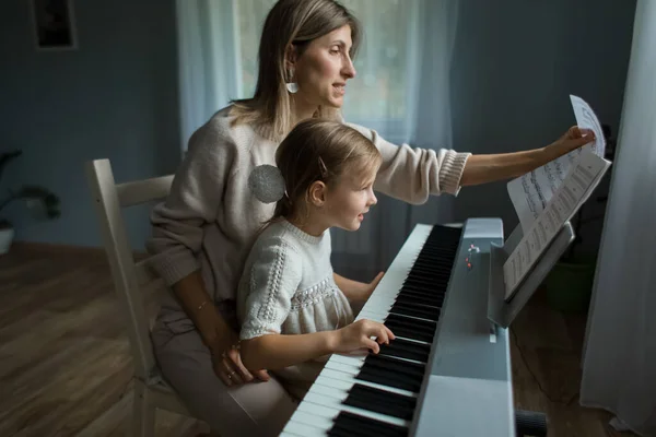 Mama i córka grają na syntezatorze w domu. — Zdjęcie stockowe