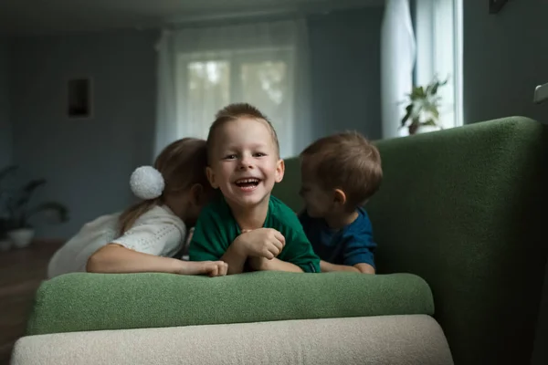 Hermosos niños tumbados en el sofá riendo en casa. —  Fotos de Stock