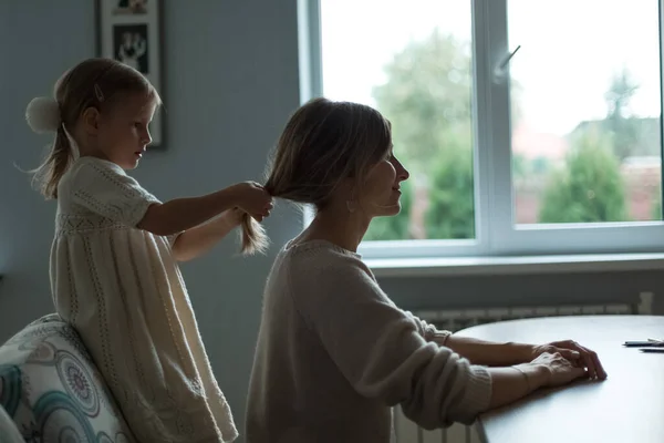 La hija trenza el pelo de sus madres. Muebles para el hogar. —  Fotos de Stock