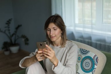 Güzel bir kız oturur ve düşünceli bir şekilde telefona bakar..