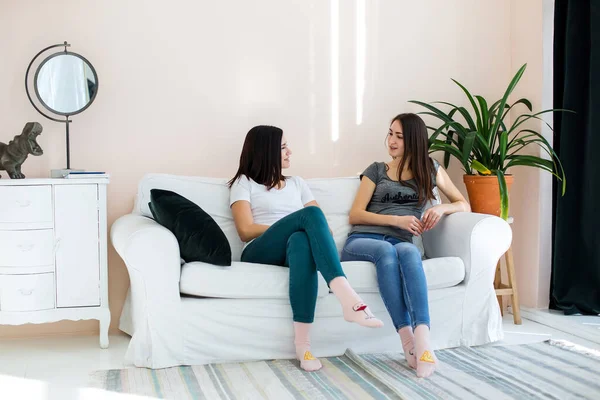 İki kız kanepede oturmuş birbirleriyle sohbet ediyorlar..