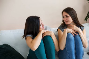 İki kız kanepede oturmuş birbirleriyle sohbet ediyorlar..