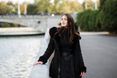 Bir kız, sıcacık giysiler içinde, deniz kenarındaki setin üzerinde duruyor..