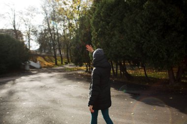 Güneşli bir günde, sıcak kıyafetler ve şapkayla parkta bir kız..