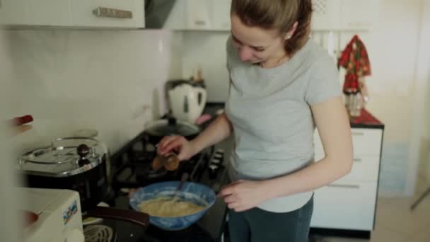 Menina mistura pratos de massa em uma placa na cozinha, uma criança passa — Vídeo de Stock