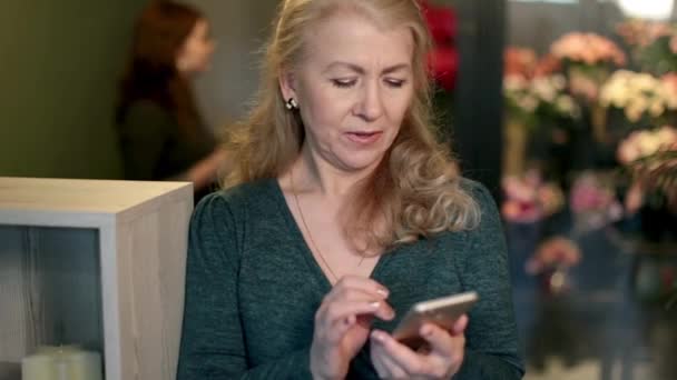 Uma mulher adulta olha para o telefone às vezes distraída. — Vídeo de Stock