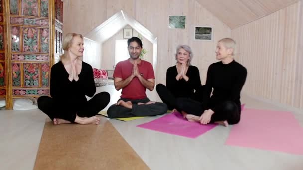 Tres mujeres mayores practican ejercicios de yoga con un instructor en casa. — Vídeos de Stock