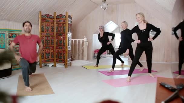 Tiga perempuan tua berlatih yoga dengan seorang instruktur di rumah. — Stok Video