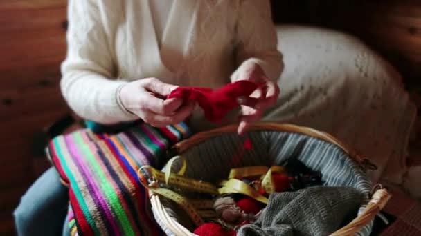 Erwachsene Hände nehmen ein gestricktes rotes Tuch auseinander. — Stockvideo