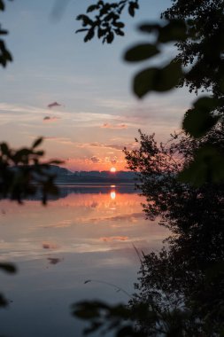 Ağaçların arasındaki gölde güzel bir gün batımı 