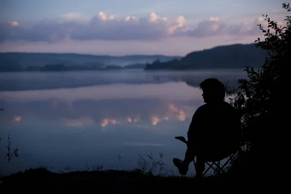 Beautiful clouds and lake in the early morning with a silhouette of a seated man