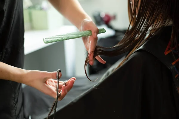 Elleri makaslı, taraklı, uzun saçlı. Güzellik salonunda bir sandalyede oturuyor..