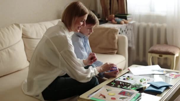 Vuxen kvinna och en tonåring sitter bakom på soffan och spelar brädspel. — Stockvideo