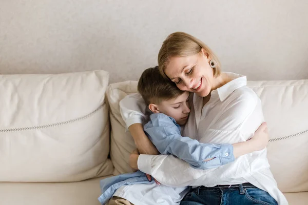 Dospělá žena sedí s teenagerem na gauči, klábosí a objímají. — Stock fotografie