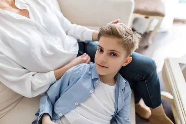 Chlapec leží na klíně ženy a dívá se přímo do kamery. — Stock fotografie