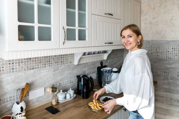 Yetişkin bir kadın mutfakta duruyor ve elinde krep tutuyor..