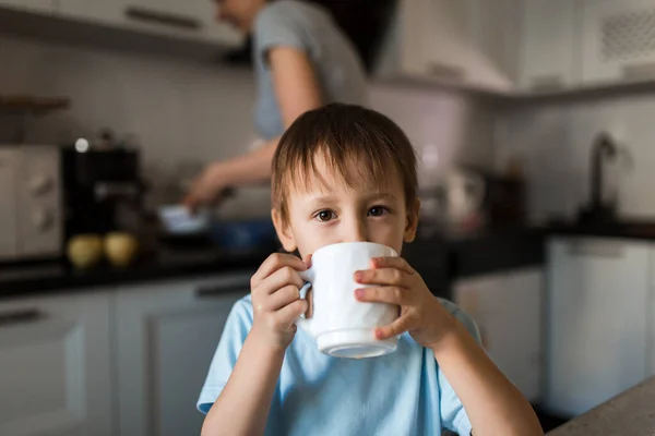 Çocuk fincandan çay içiyor ve kameraya bakıyor..