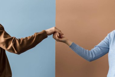 İki el parmak uçlarıyla birleşir ve farklı arkaplanda bir yumruğa dönüşür.