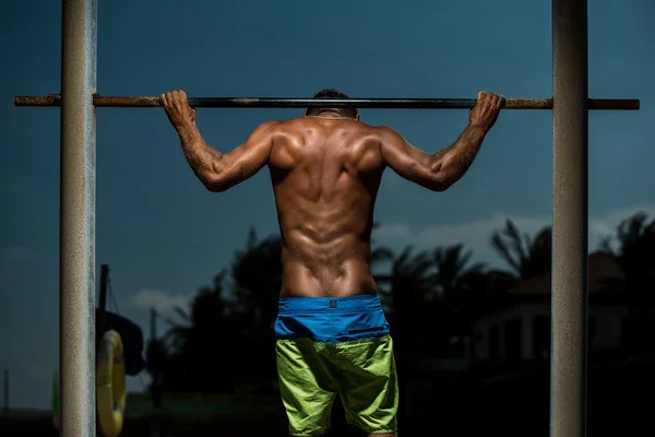 Atleta haciendo pull-up en la barra horizontal — Foto de Stock