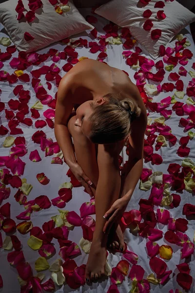 Femme au lit avec des roses — Photo