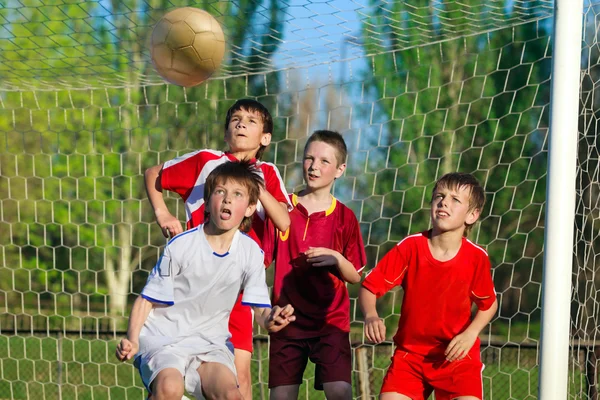 Quatre garçons jouant au football — Photo