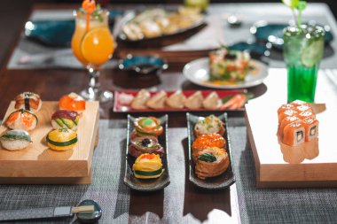 Japon mutfağı olan masanın yan görünüşü: Çiçek tabağı seti ve inari suşi çeşitli garnitürlere karşı odaklanmış..