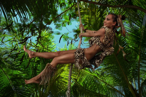 ヒョウ毛で身に着けている女性ターザンはジャングルのロープでスイング — ストック写真