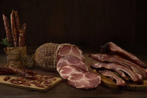 Smoked pork sausage, back ribs and pork neck. Traditional various smoked meats on a wooden table with background