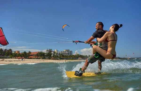 1つのカイトボード上の素敵なカップル カイトサーファーの背中に乗って海で凧揚げ — ストック写真