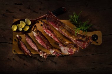 Füme domuz pirzolası, zeytinli ve rozmarine edilmiş. Koyu arkaplanda fotokopi alanı ile dosyalama yapmak için ahşap bir tahtada biraya lezzetli atıştırmalıklar