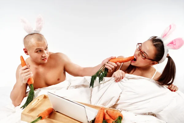 Pareja en trajes de conejo en la cama —  Fotos de Stock