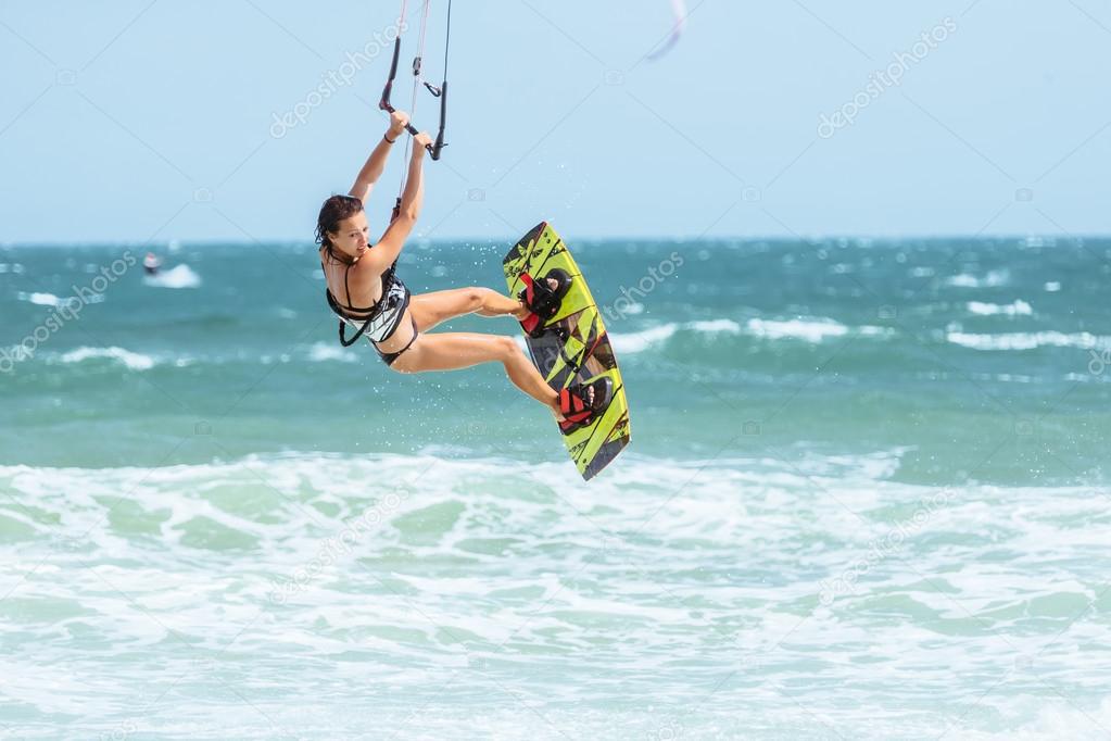 Woman kite-surfer rides in blue sea