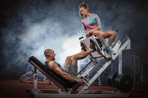 Homme faisant des presses jambes avec entraîneur — Photo