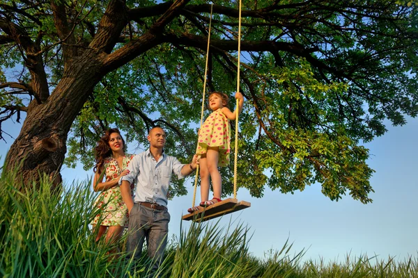 Menina no balanço com os pais — Fotografia de Stock