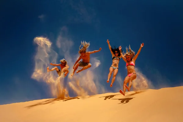 Friends jumping on the yellow sand dune. — Stock Photo, Image