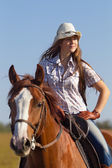 Dívka ridinga koně proti modré obloze
