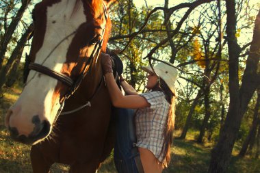 Girl straddling  horse   in garden clipart