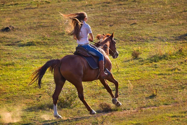 Woman in blue jeans riding a horse — Stock Photo, Image