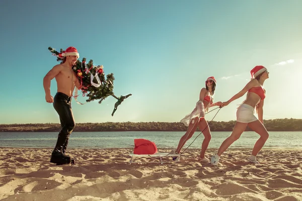Sexy Santas ciągnąc Santa na plaży — Zdjęcie stockowe