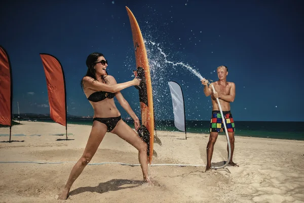 Pareja divirtiéndose con manguera en la playa — Foto de Stock