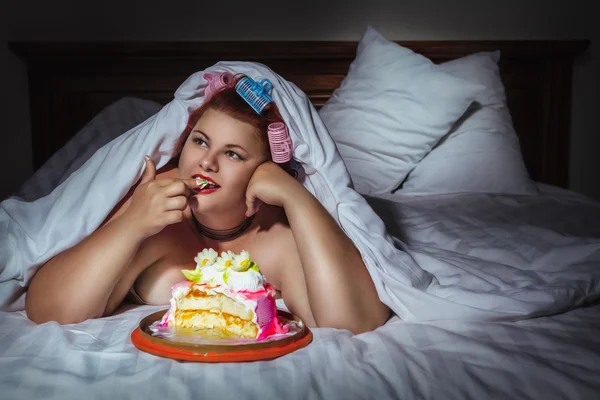 Mulher se escondendo sob o cobertor e comer biscoito — Fotografia de Stock