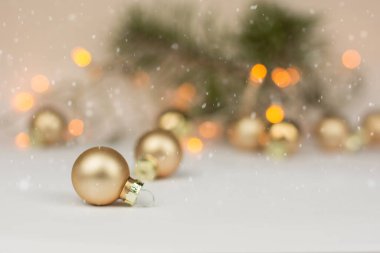 Altın noel baloları ve beyaz arka planda kar yağışı