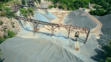 Açık çukur madenciliğindeki kum fabrikasının Arial görüntüsü. Drone kazıcıların üzerinden uçuyor ve traktör ezilmiş taşı ve kayayı çöp kamyonuna yüklüyor. 4k stok görüntüsü.