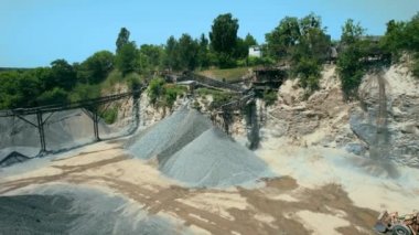 Açık çukur madenciliğindeki kum fabrikasının Arial görüntüsü. Drone kazıcıların üzerinden uçuyor ve traktör ezilmiş taşı ve kayayı çöp kamyonuna yüklüyor. 4k stok görüntüsü.