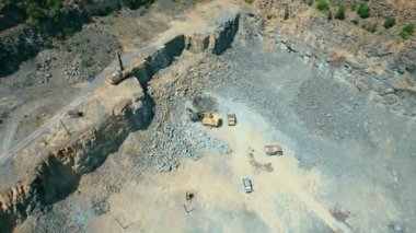 Açık çukur madenciliğindeki kum fabrikasının Arial görüntüsü. Drone kazıcıların üzerinden uçuyor ve traktör ezilmiş taşı ve kayayı çöp kamyonuna yüklüyor. 4k stok görüntüsü.