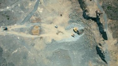 Açık çukur madenciliğindeki kum fabrikasının Arial görüntüsü. Drone kazıcıların üzerinden uçuyor ve traktör ezilmiş taşı ve kayayı çöp kamyonuna yüklüyor. 4k stok görüntüsü.