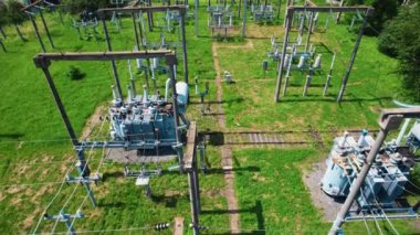 Transformatörler, elektrik kuleleri ve elektrik hatları bir elektrik santralinin zeminini kapatıyor. 4k stok görüntüsü.