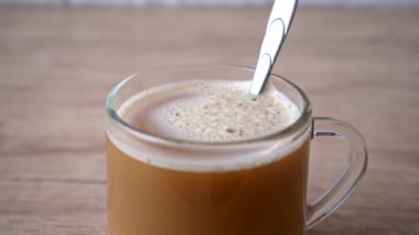 Bir adam bir fincan aromatik kapuçinonun içinde şeker karıştırır. 4k stok görüntüsü.